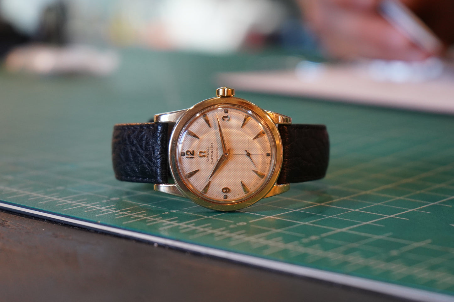 Vintage watch with a black strap on a green cutting mat
